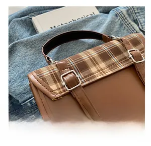 Close-up of vintage brown leather backpack with plaid pattern flap and metal buckles