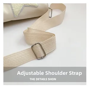 Close-up of beige messenger bag featuring adjustable strap and plush star patch