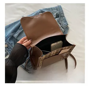 Detail of a brown plaid crossbody bag interior with compartments for phone and cards