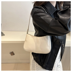 Model wearing a minimalist cream half-moon underarm bag with sleek dual stitching detail