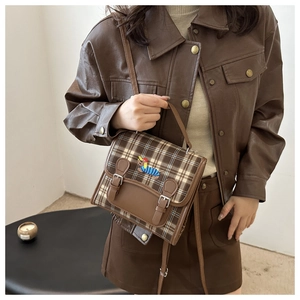 Detail view of brown plaid crossbody bag featuring colorful dachshund embroidery and leather straps