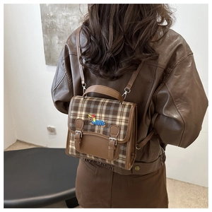 Detail of vintage brown plaid mini backpack featuring dog embroidery on a model