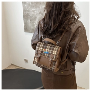 Detailed close-up of brown plaid mini backpack with leather flap and dog embroidery