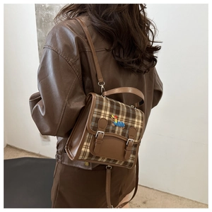 Close-up of retro plaid backpack featuring a cute dachshund embroidery and buckle detail