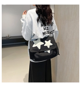 Detail view of large black canvas tote bag with white plush star patches on female model