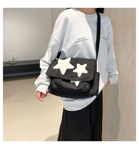 Detail of black canvas messenger bag featuring a fuzzy white star patch and adjustable strap
