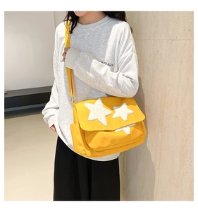 Close-up of yellow canvas messenger bag featuring white star appliques and side pocket