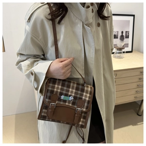 Detail of vintage brown plaid crossbody bag featuring cute puppy embroidery and silver buckles