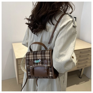 Rear view of model wearing a vintage brown plaid backpack with dog embroidery detail