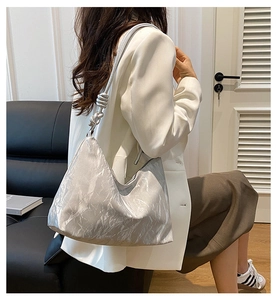 Detail of silver metallic hobo bag featuring a knotted handle and pleated texture design