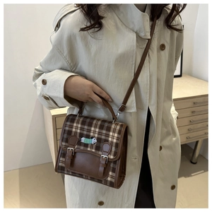 Detail of British style plaid backpack featuring dog embroidery and leather straps