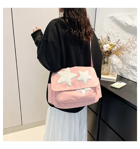 Rear view of a pink crossbody tote bag with white plush stars and adjustable strap
