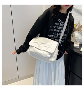 White large capacity canvas messenger bag with star patches worn by a model in a casual outfit