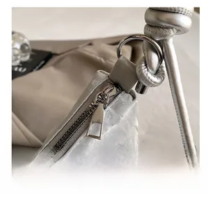 Detailed close-up of smooth metal zipper and silver ring hardware on a textured tote bag