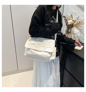 Detailed view of the white canvas shoulder bag featuring fuzzy plush star patches