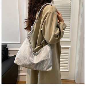Silver hobo bag with marble texture and knotted strap shown on model in beige coat