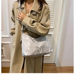 Silver metallic pleated shoulder bag with knotted strap styled on casual trench coat