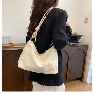Close-up of cream-colored leather tote bag featuring unique thick knotted shoulder strap