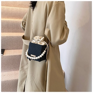 Detailansicht einer schwarzen Beuteltasche mit großen Perlenhenkeln und goldener Kette