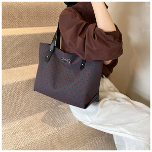 Close-up of the heart print tote bag with metallic bow detail worn by a model