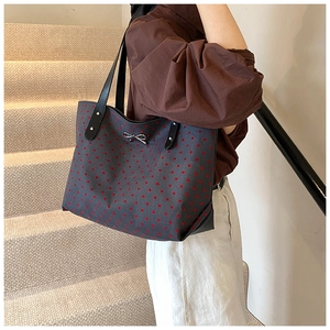 Detail of grey tote bag with red heart pattern and silver metallic bow decoration