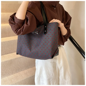 Detail of grey canvas tote bag with red heart print and silver metallic bow buckle accent