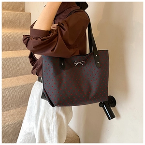 Close-up of a dark grey canvas tote bag with red heart patterns and silver bow detail