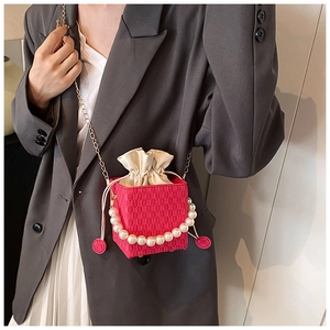 Detail of rose red woven mini bag with pearl handle and golden chain shoulder strap