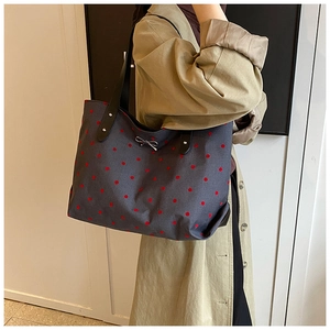 Polka dot canvas tote bag featuring premium black leather handles and metal bow detail