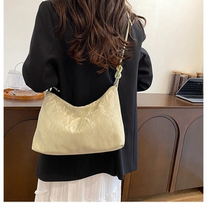 Detail of hobo shoulder bag featuring soft pleated texture and decorative knot strap