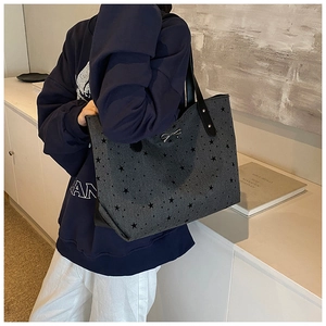 Detail of grey star print tote bag with silver metal bow and sturdy black faux leather handles