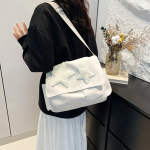 White canvas messenger bag with plush star patches and adjustable strap on a model