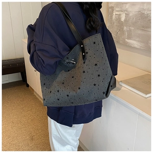 Detail view of canvas tote bag with star print and silver metal bow ornament on shoulder