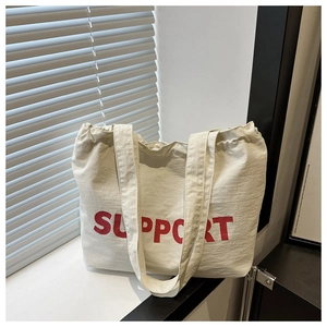 Detail of off-white canvas tote bag featuring bold red SUPPORT text and fabric texture