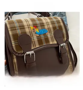 Détail du sac à dos vintage montrant le tissu à carreaux marron et la broderie animale