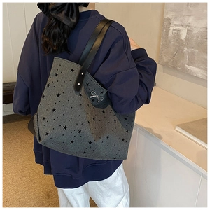 Detailed view of the large grey star-print tote bag with bow detail worn by a model