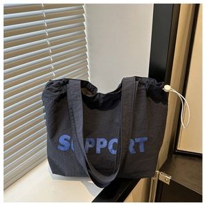 Detail of dark blue nylon tote with SUPPORT lettering and white drawstring closure