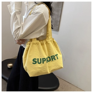 Detail of yellow drawstring canvas tote with green SUPPORT text on durable nylon fabric