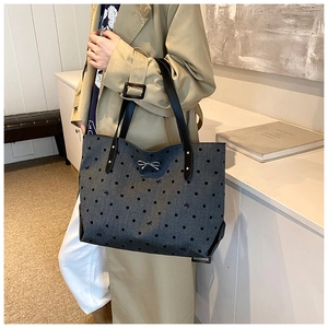 Detailed view of dark grey polka dot tote bag with a small silver metal bow buckle