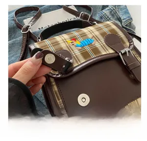 Détail de la broderie teckel et fermoir magnétique sur le sac à dos rétro à carreaux