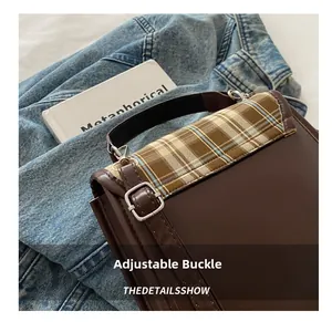 Détail de la boucle argentée et du motif à carreaux sur un sac à dos en cuir marron
