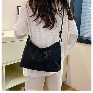 Close-up of black pleated hobo bag with knot shoulder strap detail and silver hardware