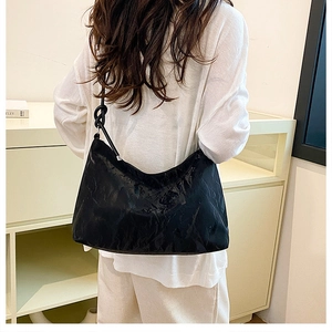 Detail of black crinkled texture tote bag featuring a decorative knotted shoulder strap