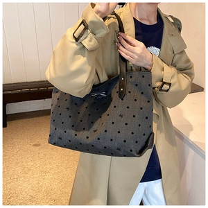 Close-up of gray polka dot tote bag with black bow embroidery and metal buckle detail