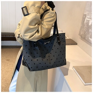 Detailed close-up of dark grey polka dot tote bag with silver bow charm on a model