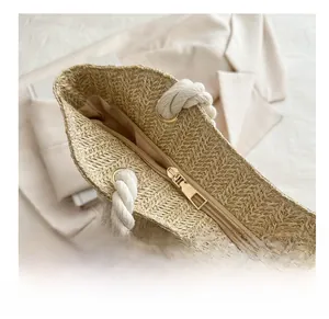 Détail du sac en paille tissée montrant la fermeture éclair et la poignée en corde