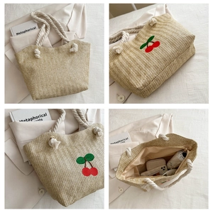 Détail d'un sac cabas en paille avec broderie cerise et poignées en corde de coton