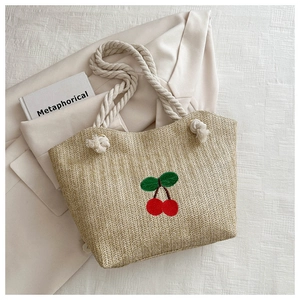 Gros plan du sac cabas en paille tissée avec broderie cerise et anse en coton