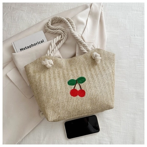 Détail du sac cabas en paille avec broderie cerise et anses en corde de coton blanc