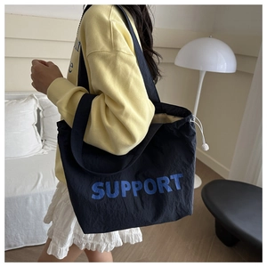 Detail of navy tote bag with Support print, white drawstring, and metallic buckle
